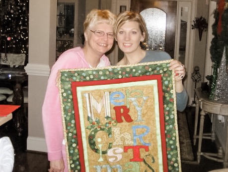 Mother and Daughter holding Christmas Quilt